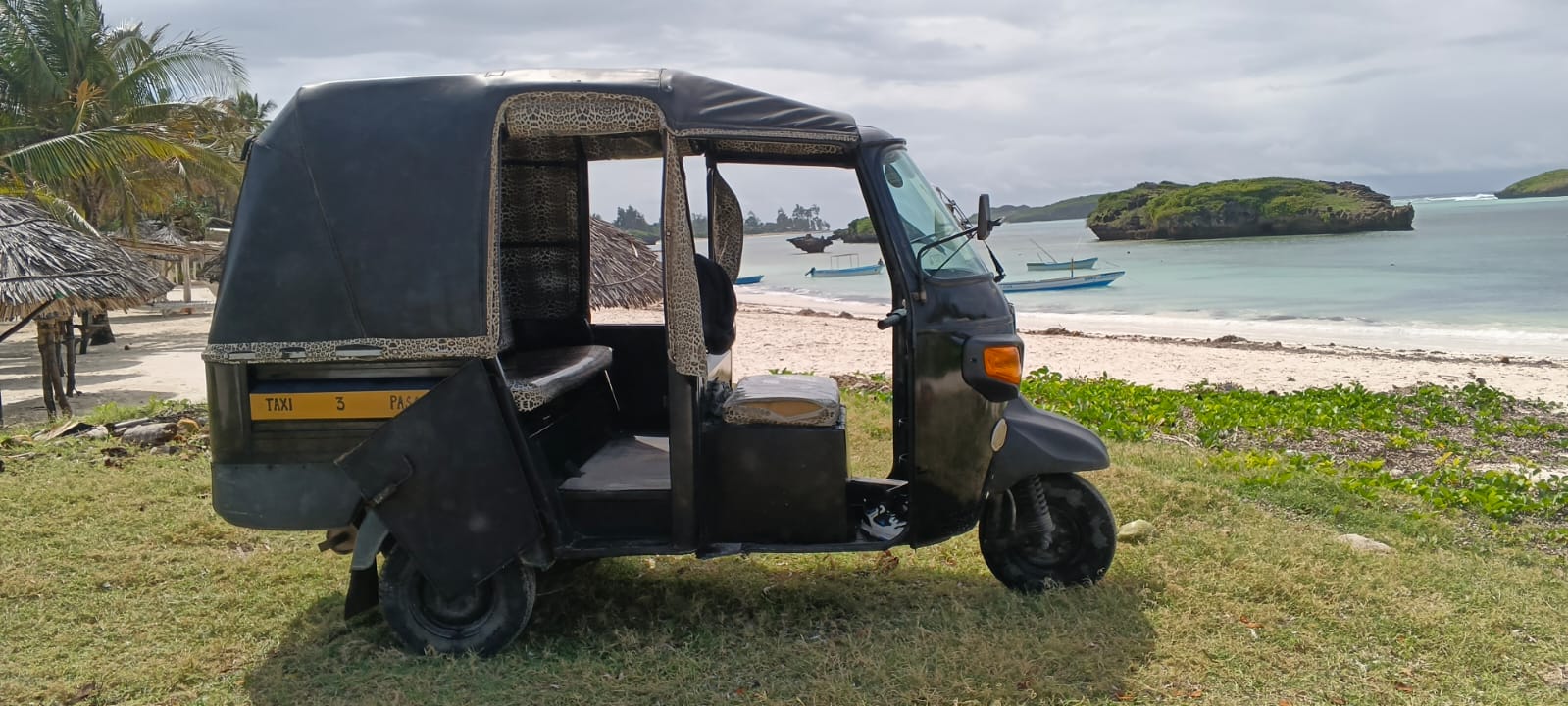 Tuk tuk parked by the turquoise ocean at Watamu