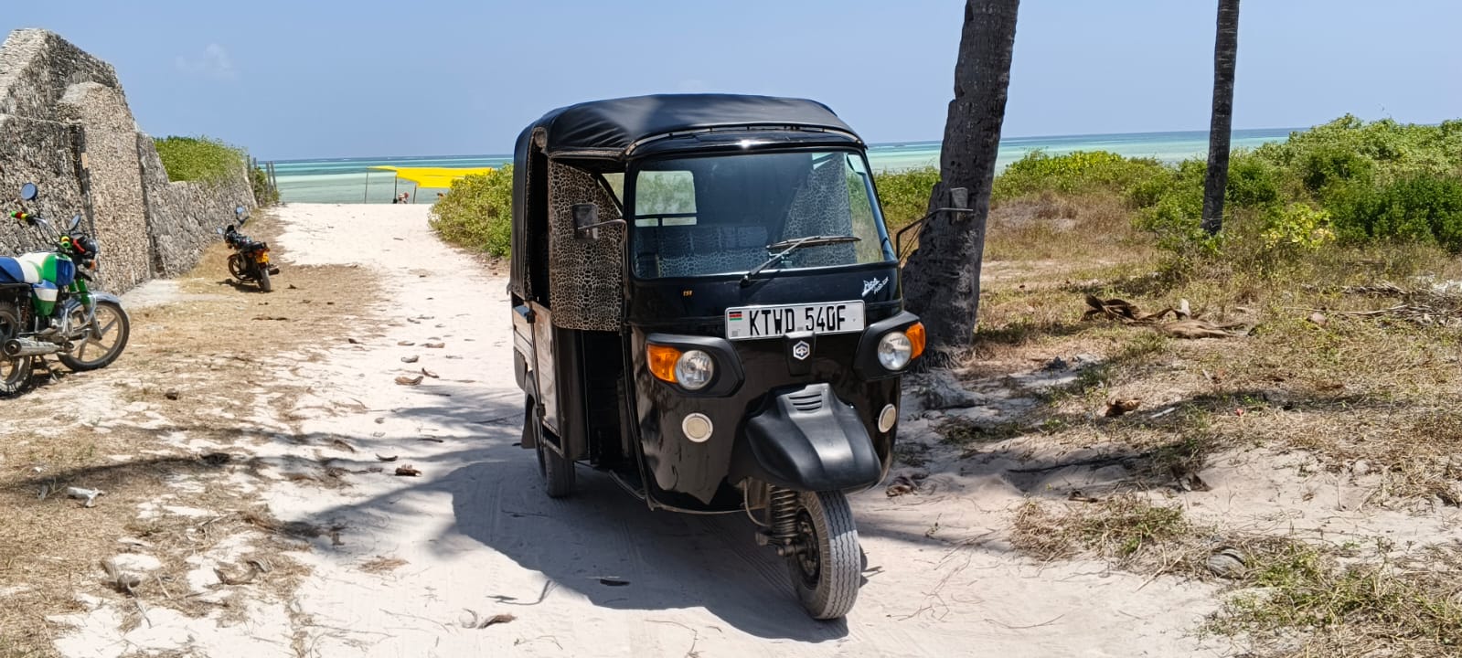 Black tuk tuk on a sandy path leading to Watamu beach