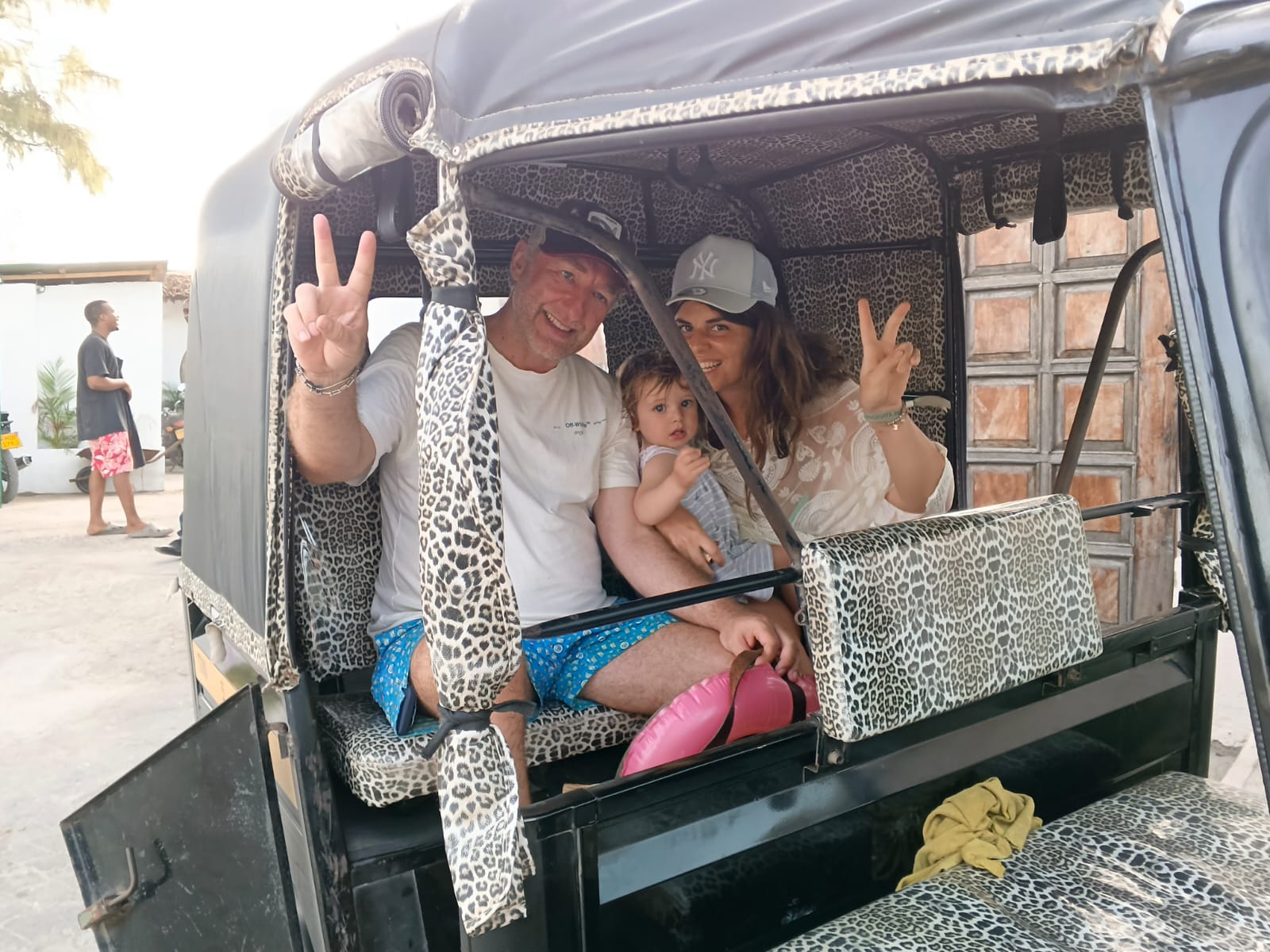 Family with a baby smiling in the back of Mose's tuk tuk in Watamu
