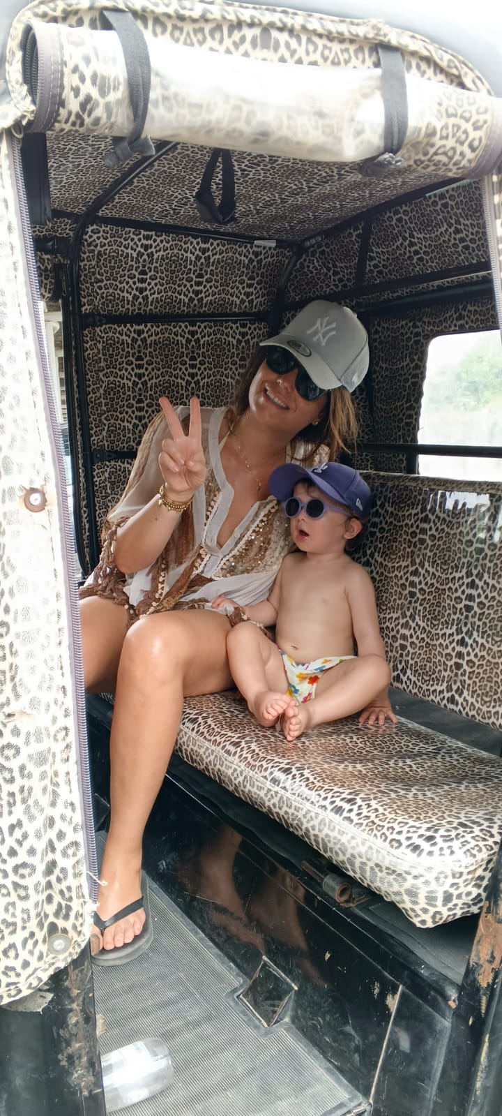 Mother and baby relaxing on the leopard print seats of the tuk tuk