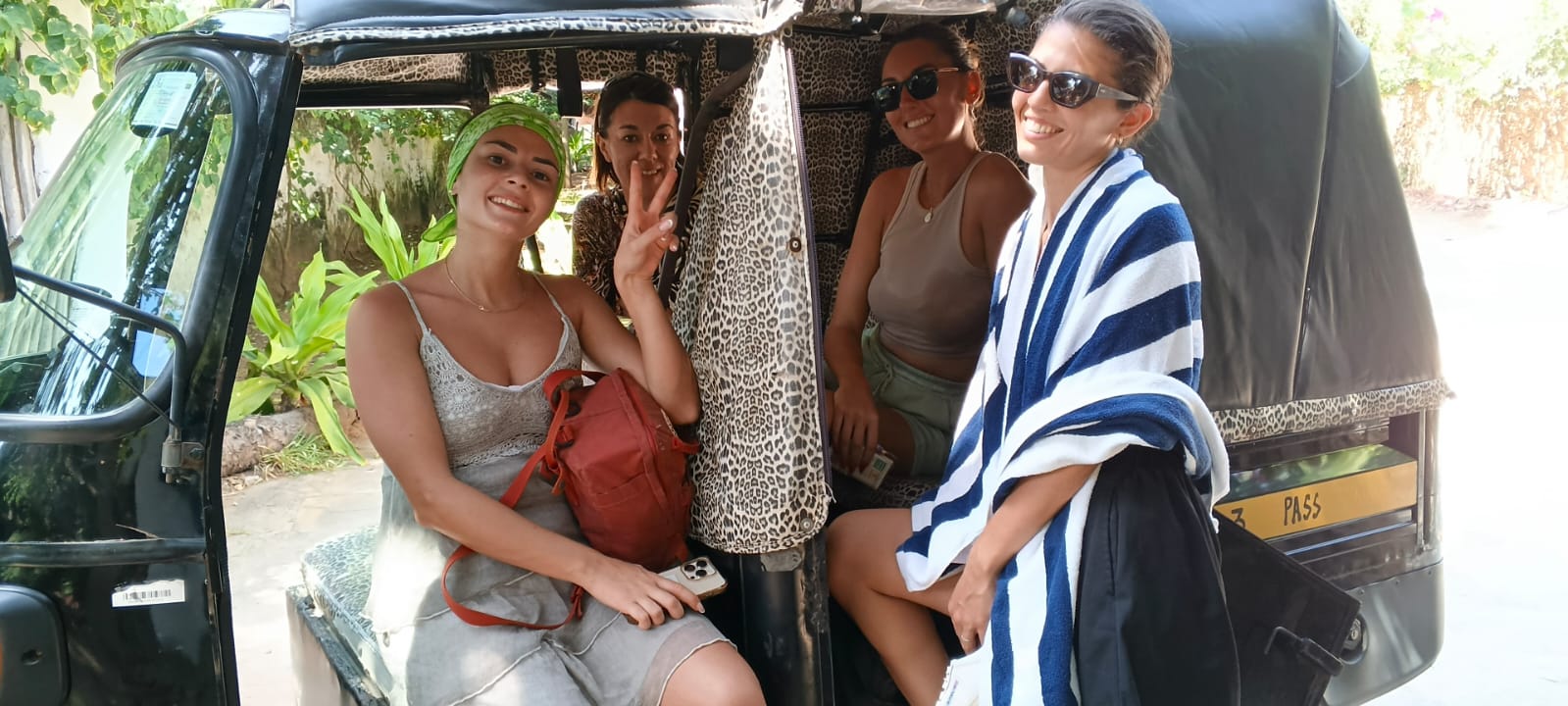 Group of happy tourists riding in Mose's tuk tuk in Watamu